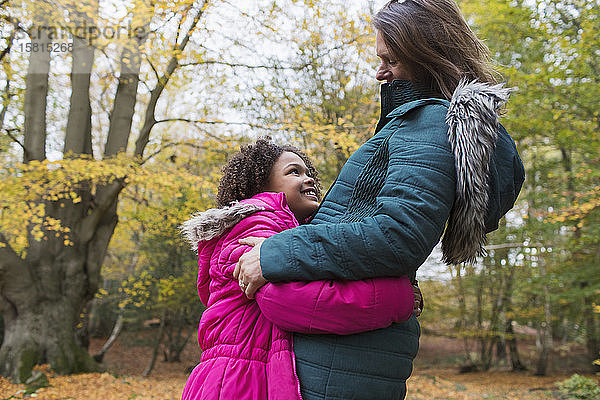 Glückliche Mutter und Tochter umarmen sich im Herbstwald