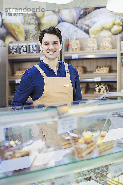 Porträt eines selbstbewussten Mannes  der an einer Bäckereivitrine im Supermarkt arbeitet