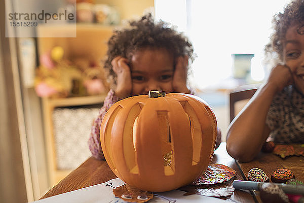 Porträt süßes Mädchen schnitzen Halloween-Kürbis am Tisch