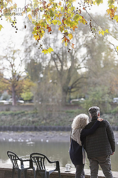 Zärtliches aktives Seniorenpaar am Herbstparkteich