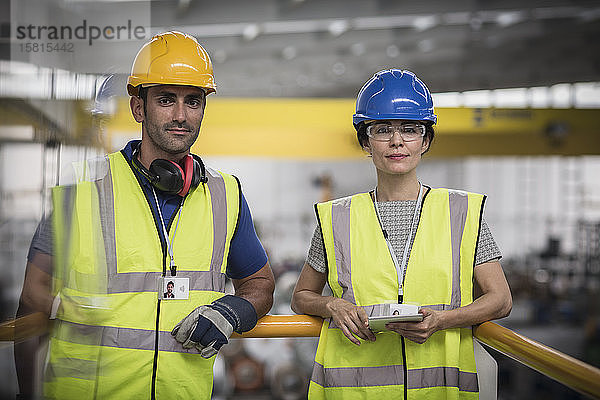 Porträt selbstbewusster Aufsichtspersonen mit digitalem Tablet auf einer Plattform in einer Fabrik