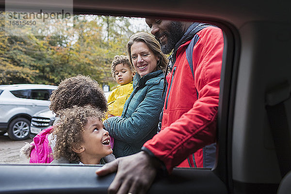 Glückliche multiethnische Familie vor dem Auto