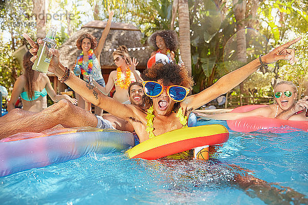 Porträt übermütiger junger Freunde beim Trinken und Spielen im Sommerschwimmbad