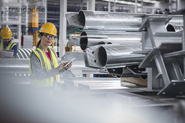 Porträt einer selbstbewussten Arbeiterin mit digitalem Tablet in einem Stahlwerk