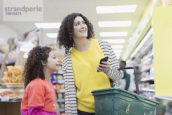 Mutter und Tochter mit Smartphone beim Einkaufen im Supermarkt