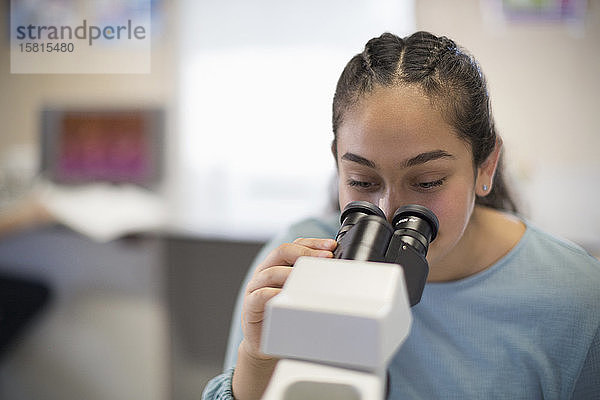 Studentin mit Mikroskop im Klassenzimmer
