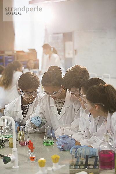 Studenten führen ein wissenschaftliches Experiment durch  indem sie eine Flüssigkeit in einen Becher im Laboratorium gießen