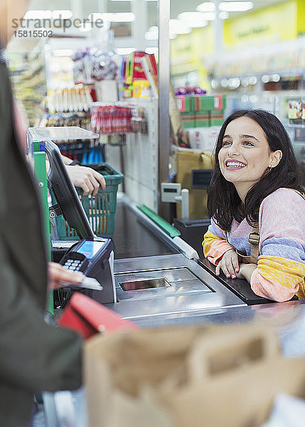 Freundliche Kassiererin hilft Kunden an der Supermarktkasse