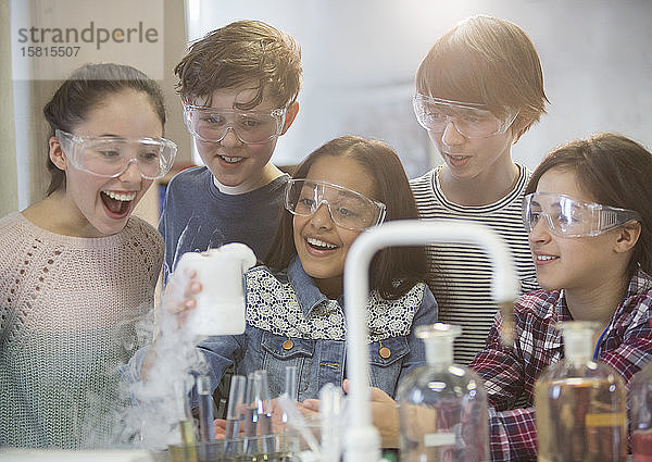 Überrumpelte Schüler  die ein wissenschaftliches Experiment durchführen und eine chemische Reaktion im Klassenlabor beobachten
