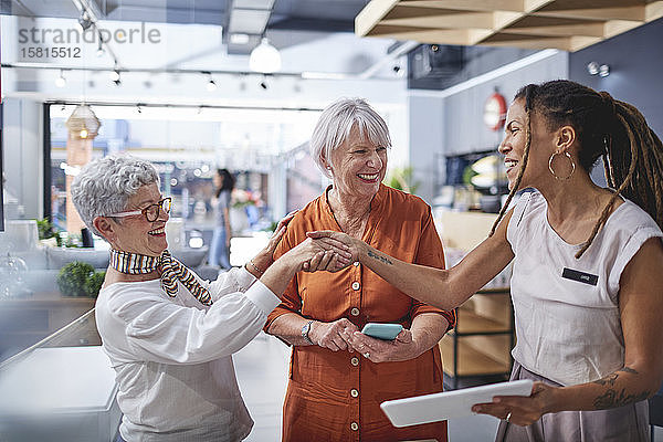 Innenarchitektin beim Händeschütteln mit Frauen  die in einem Geschäft für Wohnkultur einkaufen