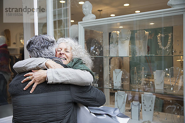 Älteres Paar  das sich umarmt  Schaufensterbummel in einem Juweliergeschäft