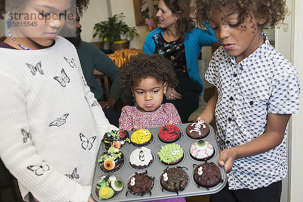 Geschwister mit dekorierten Halloween-Cupcakes