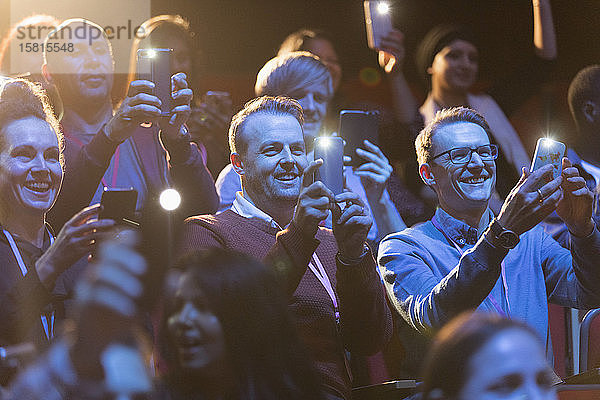 Lächelndes Publikum mit Smartphone-Taschenlampen