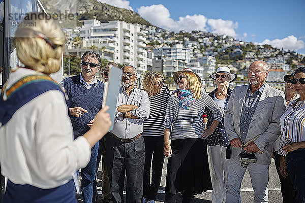 Aktive ältere Touristenfreunde hören dem Reiseleiter zu