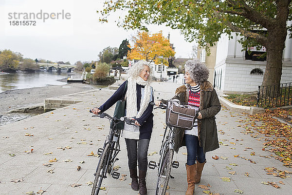 Lächelnde aktive ältere Frauen  die im Herbst im Park Fahrrad fahren