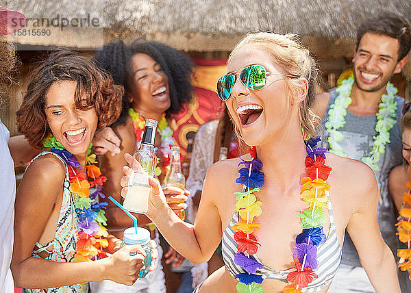 Verspielte Freunde  die Leis tragen  trinken und feiern am sonnigen Sommerpool