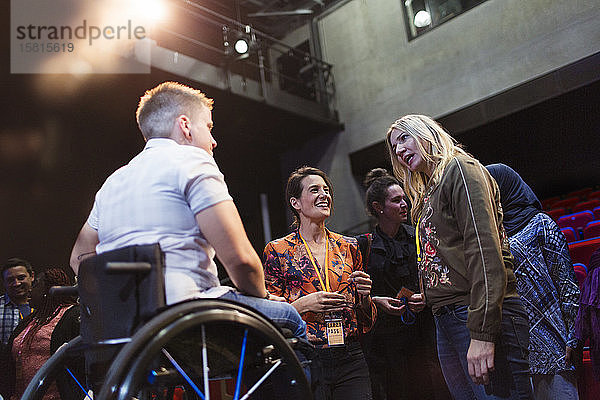 Frauen im Konferenzpublikum im Gespräch mit einem Redner im Rollstuhl