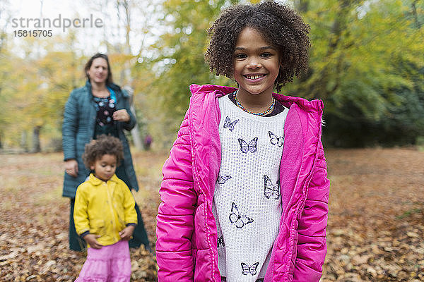 Portrait glückliches Mädchen mit Familie im Herbstwald