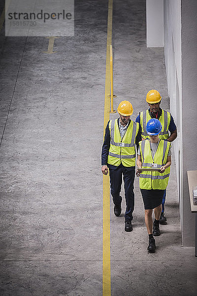 Aufsichtsperson und Arbeiter mit digitalem Tablet bei einem Spaziergang in der Fabrik