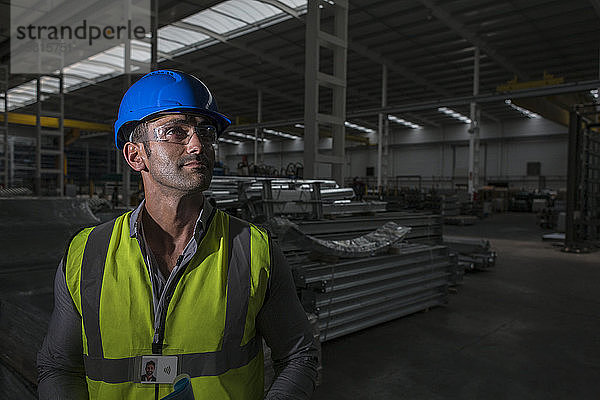 Porträt selbstbewusster männlicher Arbeiter  der in einer dunklen Fabrik wegschaut