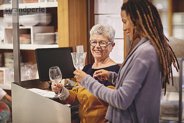 Lächelnder Angestellter hilft Frau beim Einkaufen von Weingläsern