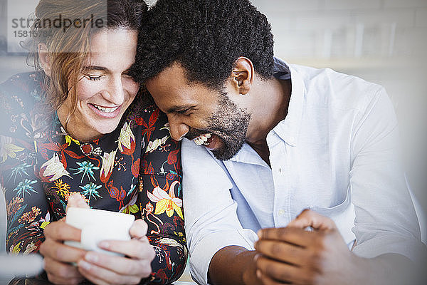 Zärtliches  lächelndes  multiethnisches Paar beim Kaffeetrinken