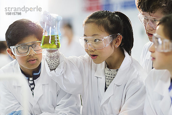 Neugierige Schüler  die eine Flüssigkeit in einem Becherglas untersuchen und ein wissenschaftliches Experiment im Labor durchführen