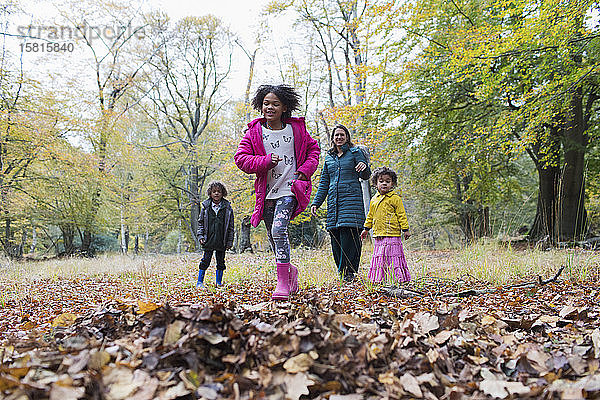Glückliche Familie beim Laufen und Spielen im Herbstwald