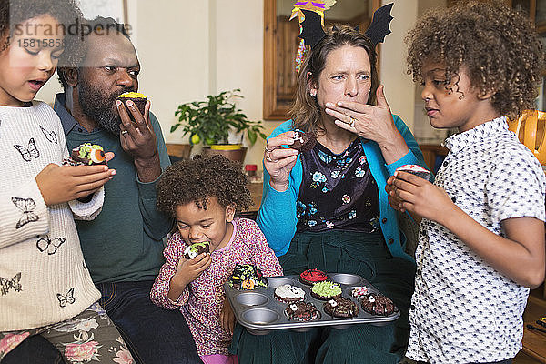 Multiethnische Familie isst dekorierte Halloween-Cupcakes