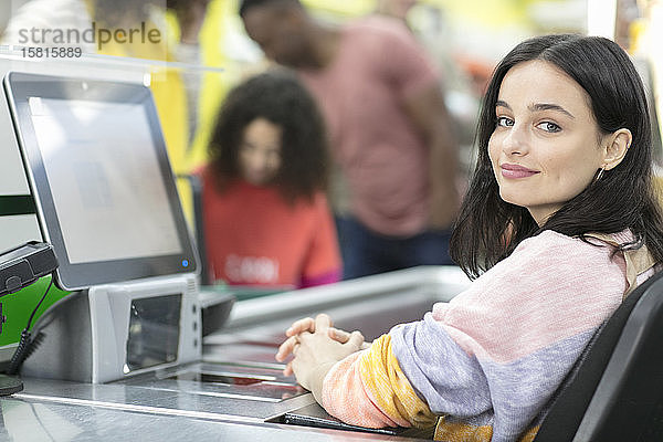 Porträt zuversichtlich  junge weibliche Kassiererin arbeitet an der Kasse im Supermarkt