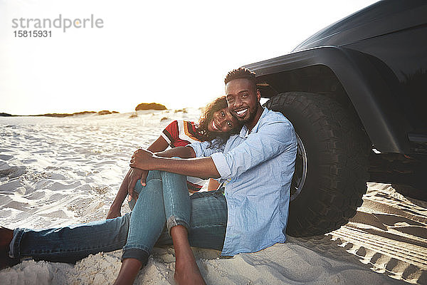 Porträt zärtliches junges Paar entspannt sich im Jeep am Strand