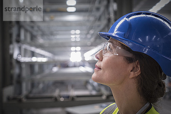 Profil einer nachdenklichen Arbeiterin  die in einer Fabrik nach oben schaut