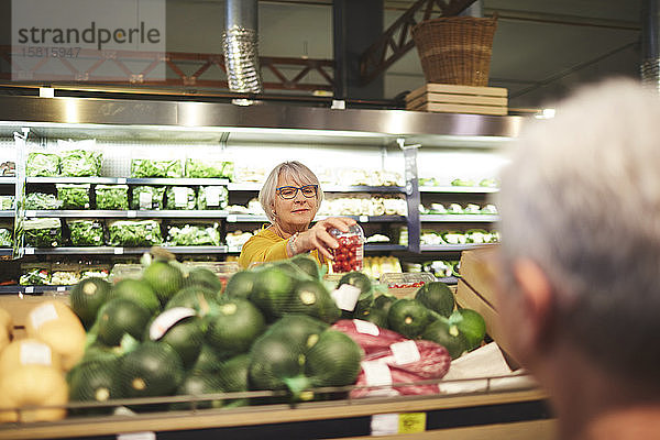 Ältere Frau beim Einkaufen von Tomaten in der Gemüseabteilung eines Supermarkts