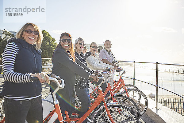 Porträt lächelnd  zuversichtlich  aktiv ältere Touristen Freunde auf Fahrrädern auf sonnigen Strandpromenade