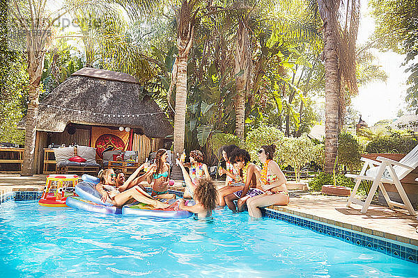 Junge Freunde hängen am tropischen Sommerschwimmbad ab