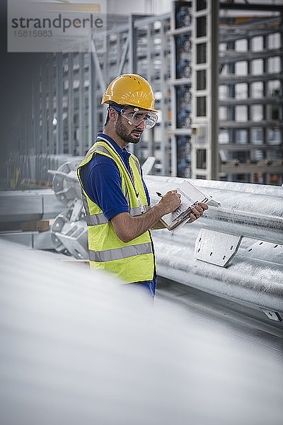 Männlicher Arbeiter mit Klemmbrett bei der Arbeit in einer Stahlfabrik