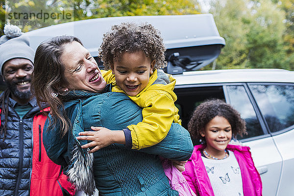 Glückliche Mutter und Tochter  die sich vor dem Auto umarmen