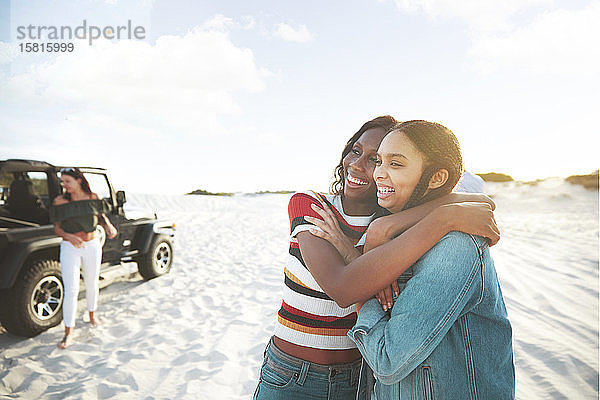 Glückliche junge Frauen  die sich umarmen und einen Ausflug zum Strand genießen