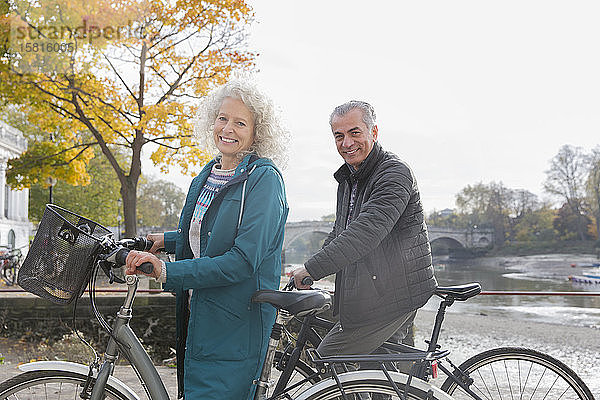 Porträt lächelnd Senior Paar Radfahren entlang Herbst Fluss