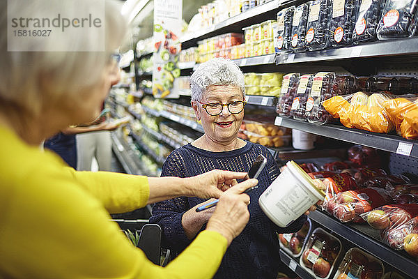 Ältere Frauen mit Smartphone beim Lebensmitteleinkauf im Supermarkt