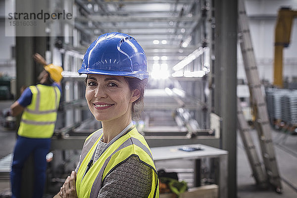 Porträt einer lächelnden  selbstbewussten Arbeiterin in einer Fabrik