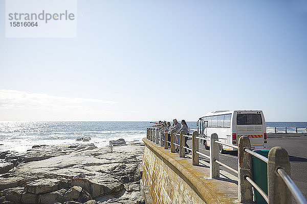 Touristen mit Blick auf das sonnige Meer vor dem Reisebus