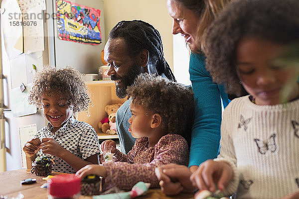 Multiethnische Familie beim Verzieren von Cupcakes am Tisch