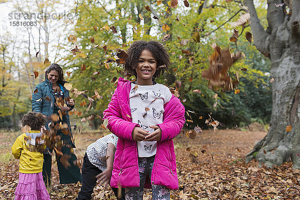 Porträt glückliches Mädchen spielt mit Familie im Herbst Blätter