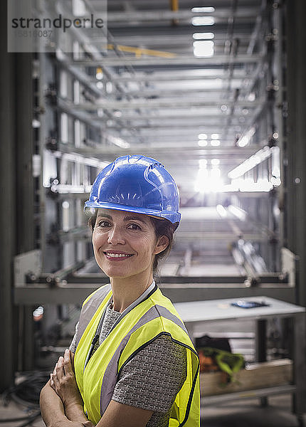 Porträt einer lächelnden  selbstbewussten Arbeiterin in einer Stahlfabrik