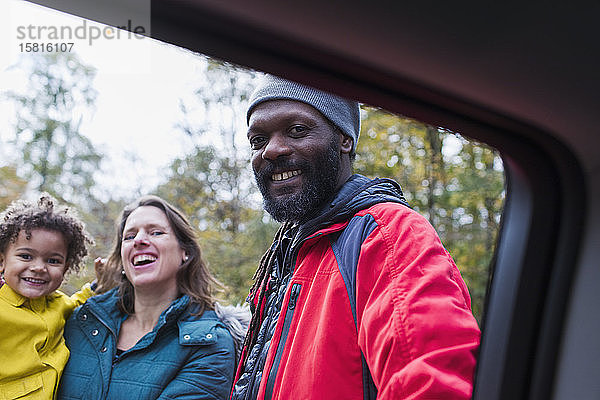Porträt einer glücklichen multiethnischen Familie vor dem Auto