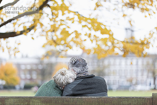 Zärtliches älteres Paar kuschelt auf einer Bank im Herbstpark