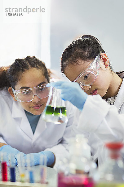 Studentin  die eine Flüssigkeit in einem Becherglas untersucht und ein wissenschaftliches Experiment in einem Laboratorium durchführt