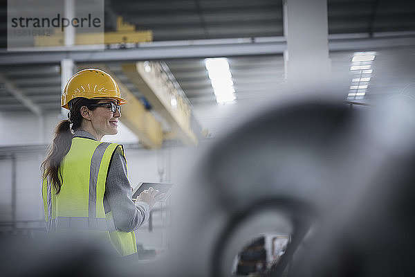 Selbstbewusste Arbeiterin mit digitalem Tablet in einem Stahlwerk