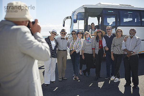Aktive ältere Touristenfreunde posieren für ein Foto vor dem Reisebus